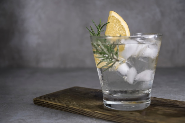 Bebida alcohólica gin tonic cocktail con limón, romero y hielo