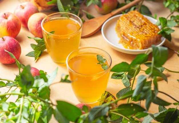 Una bebida amarilla en un vaso sobre una mesa de madera junto a un panal de miel