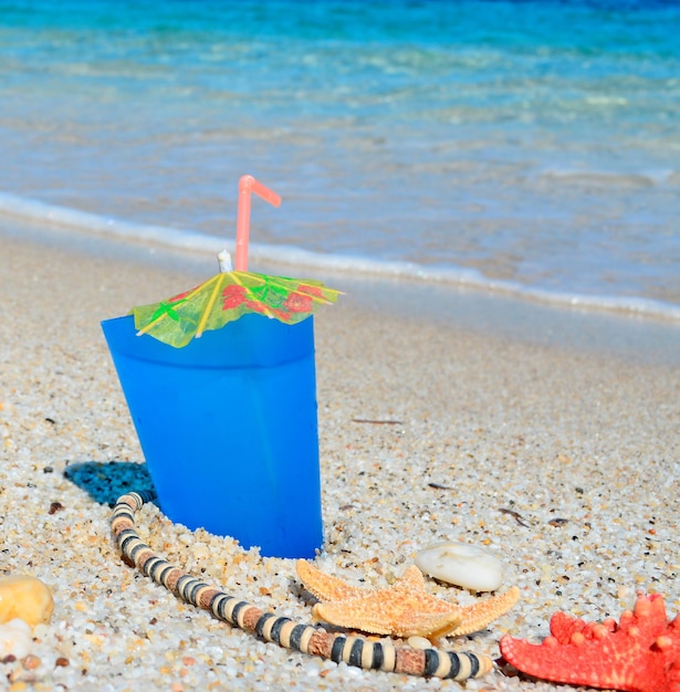 Bebida azul com conchas e colar à beira-mar