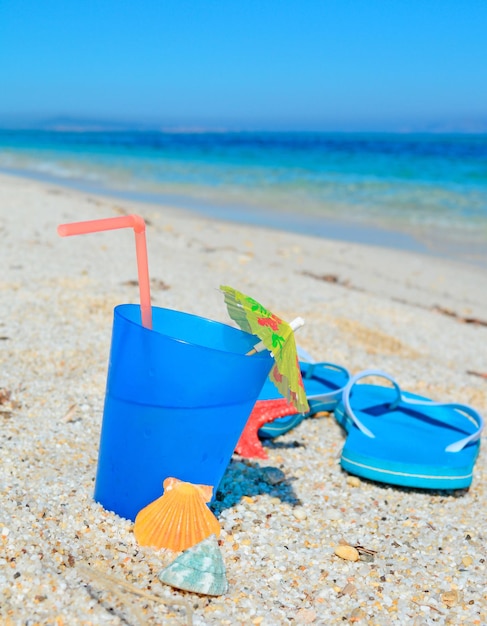 Bebida azul com sandálias em uma costa tropical