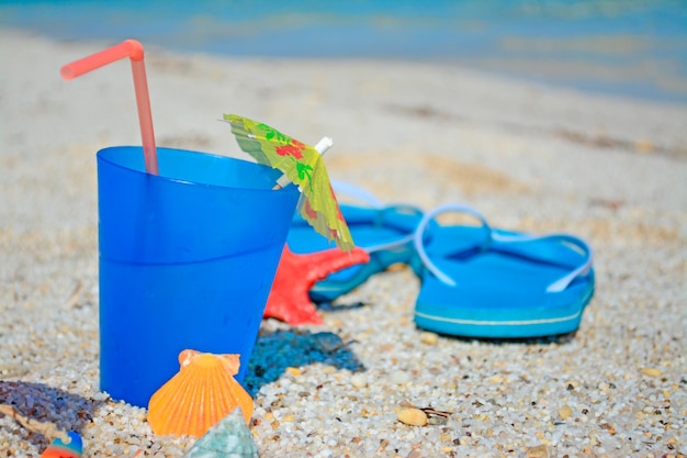 Bebida azul con sandalias en una costa tropical