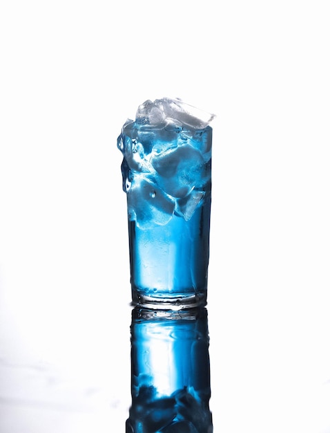Bebida azul en vaso contra un fondo gris
