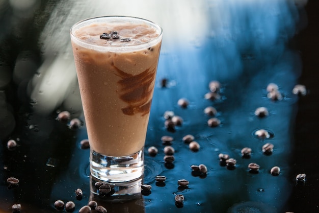 Bebida de café helado con chocolate, granos de café sobre un fondo húmedo