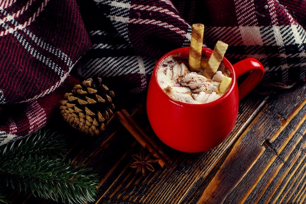 Bebida de café de invierno, cacao con crema batida y malvaviscos en una taza de cerámica roja