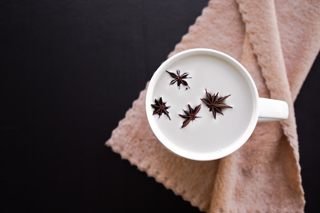 Bebida caliente para el concepto de otoño invierno. Leche caliente con frutas de especias de anís estrellado en taza blanca sobre mesa de madera. endecha plana