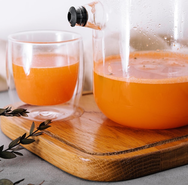 Bebida caliente de un espino amarillo en un vaso y una jarra