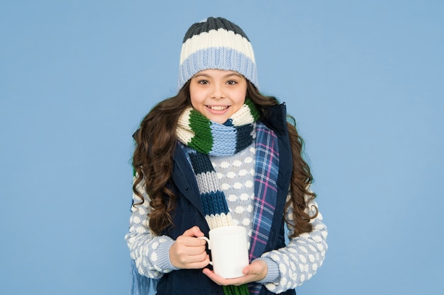 Bebida caliente. Idea para calentar. Hipster niña feliz. Moda infantil de invierno. Prendas de punto de abrigo para niños. Taza de té para bebés. Toma una bebida caliente. Beber chocolate caliente. Receta de chocolate caliente. Concepto de postre. Descanso.