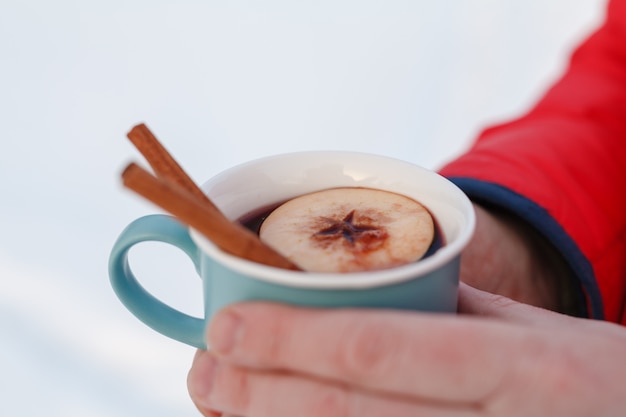 Bebida caliente de invierno en el bosque, vino caliente en manos