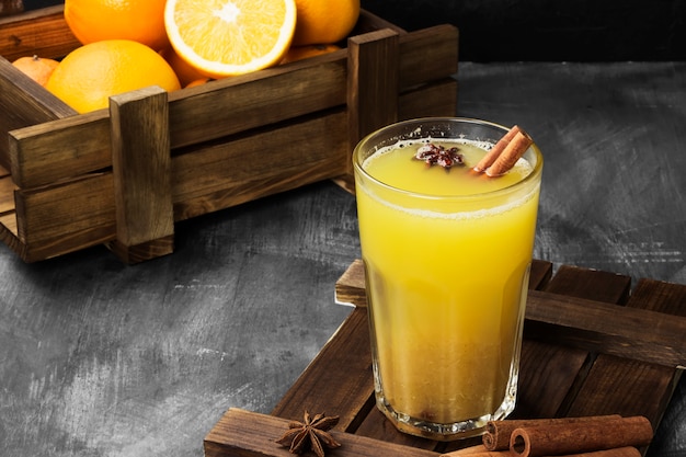 Bebida caliente de invierno de naranjas y especias sobre una superficie negra