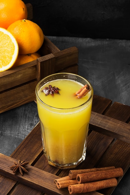 Bebida caliente de invierno de naranjas y especias sobre una superficie negra.