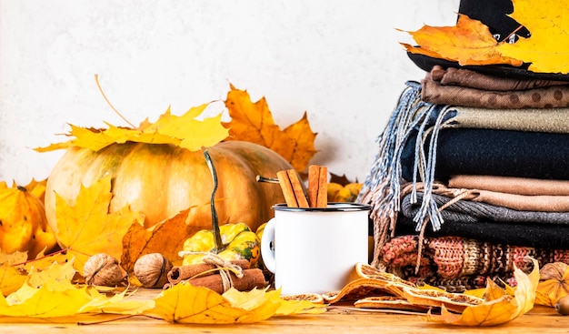 Bebida caliente de otoño en taza blanca sobre fondo de otoño con calabazas hojas caídas ropa de otoño bufandas en espacio de copia de mesa de madera rústica