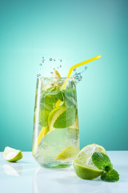 Foto bebida calmante con menta y limón vaso con agua menta y limón pulverizar sobre vidrio fondo turquesa brillante