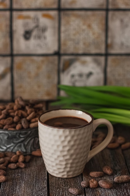 Foto bebida de chocolate caliente en una taza blanca cubos de chocolate palitos de canela y granos de café en el fondo de madera oscura