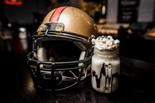 Foto bebida de chocolate con leche con malvavisco y casco de fútbol americano