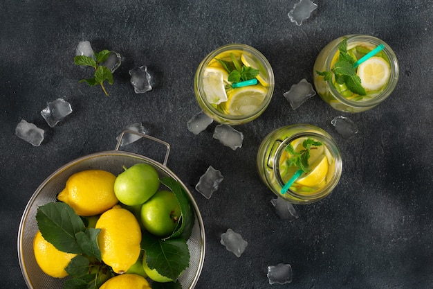 Bebida cítrica de verano. Limonada fresca con manzanas y limón en una vista superior oscura