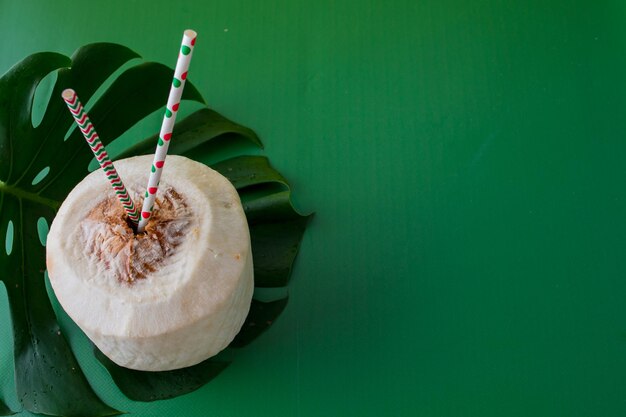 bebida de coco joven con pajitas de papel sobre un fondo verde