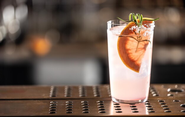 Bebida cóctel Paloma con ginebra de pomelo y soda decorada con romero