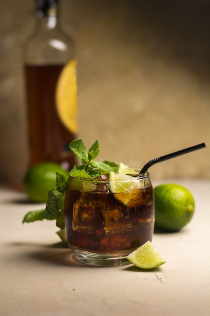 Bebida Cuba Libre con hojas de menta y trozos de lima. Bebida alcohólica con ron y cola.