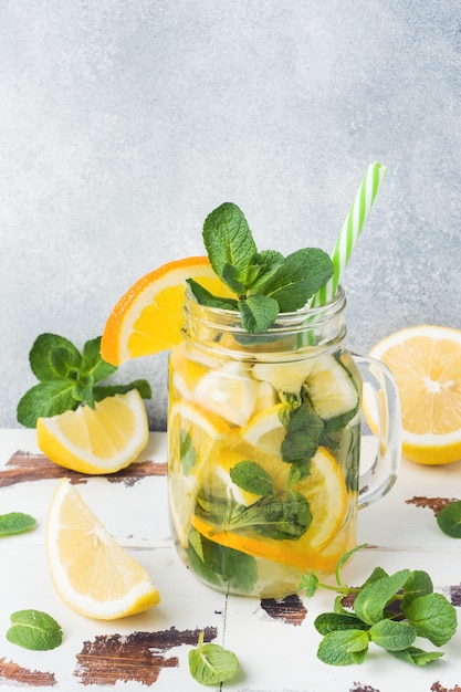 Bebida da limonada das folhas da água de soda, do limão e de hortelã no frasco no fundo claro.