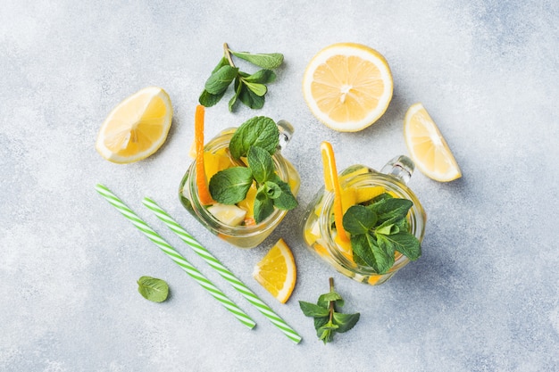 Bebida da limonada das folhas da água de soda, do limão e de hortelã no frasco no fundo claro.