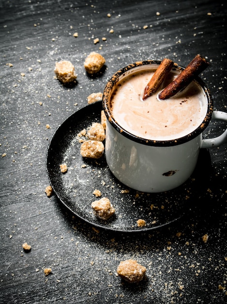 Bebida de cacau com canela e açúcar escuro em preto na mesa rústica.