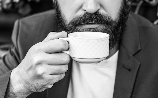 Bebida de café. Homem barbudo, mãos segurando xícaras de café quente. Hora do café. Preto e branco.