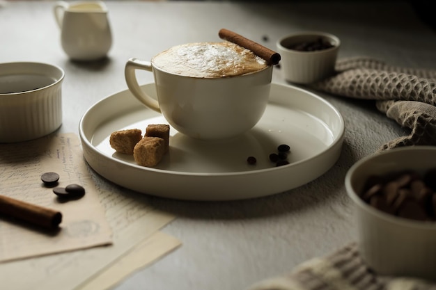 Bebida de café quente com espuma de leite e canela em uma xícara de café em grãos chocolate e especiarias