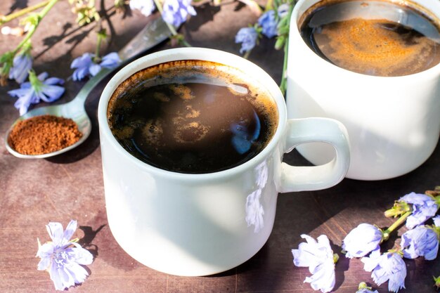 Bebida de chicória saudável em copo decorado com flores de chicória. Bebida erval, substituto do café. Foco seletivo