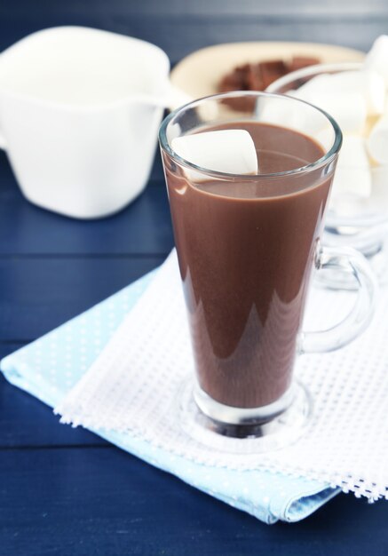 Bebida de chocolate com marshmallows na caneca, com fundo de madeira