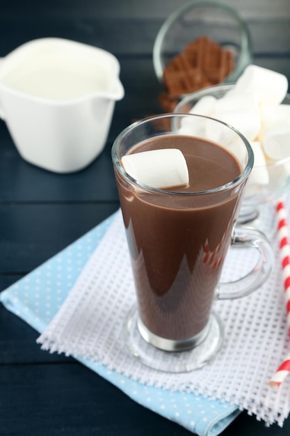 Bebida de chocolate com marshmallows na caneca, com fundo de madeira