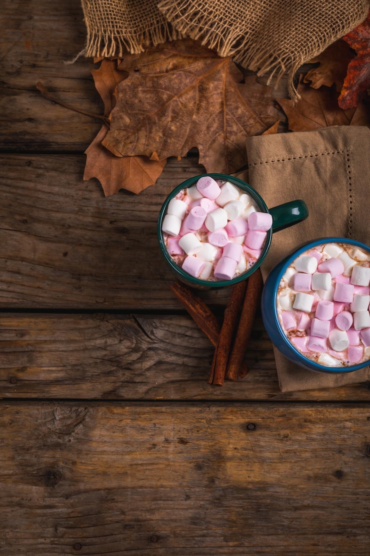 Foto bebida de chocolate quente cheia de marshmallows em copos por folhas de outono de canela com espaço de cópia
