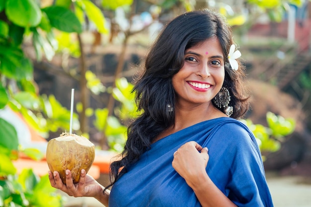 Bebida de coco de mulher indiana feliz na praia tropical