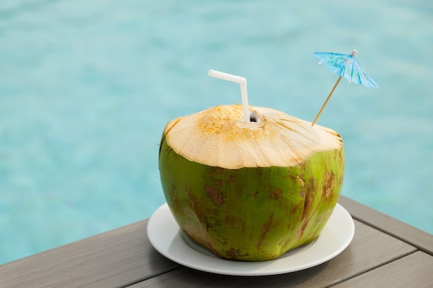 Bebida de coco fresco na mesa ao lado da piscina