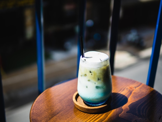 Bebida de creme de café azul com espuma em mesa de madeira em um café com fundo de iluminação