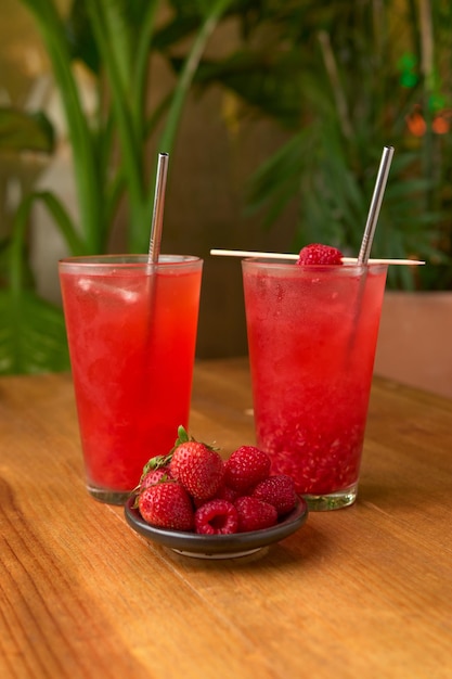 Bebida de frutas vermelhas tropicais em uma mesa de madeira com fundo vegetal