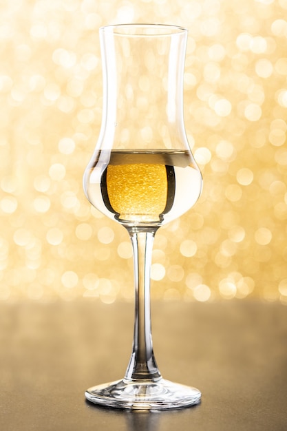 bebida de grappa dourada italiana em fundo amarelo brilhante