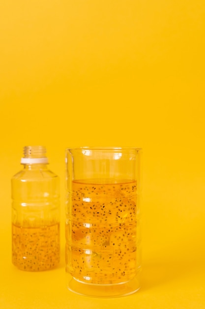 Bebida de manga com sementes de manjericão com gelo em um fundo amarelo.