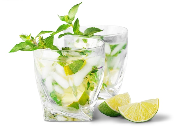 Bebida de mojito gelado, copo de álcool isolado sobre fundo branco, hortelã fresca e fatias de limão,