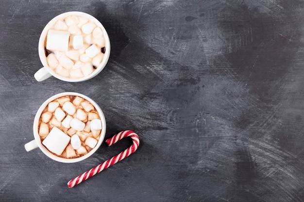 Bebida de natal. duas xícaras de chocolate quente com marshmallow e bengala