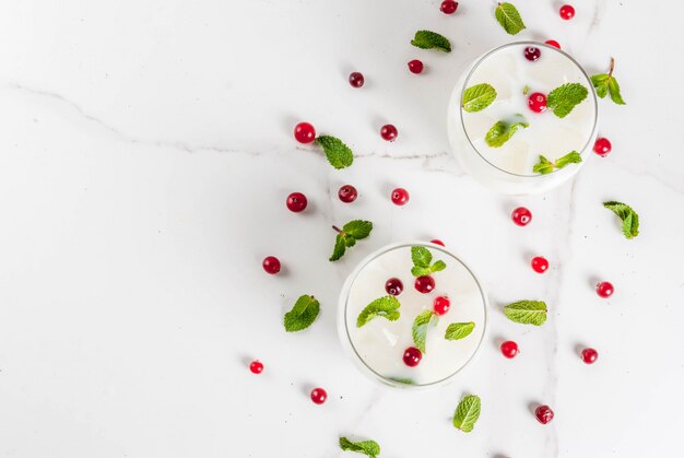 Bebida de refresco de outono e inverno white christmas mojito cocktail com cranberry e hortelã na mesa branca