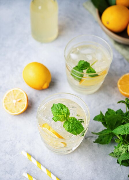 Bebida de refrigerante de limonada com limões frescos Coquetel refrescante com hortelã limão e gelo no fundo azul Conceito de bebidas frias de verão Vista superior