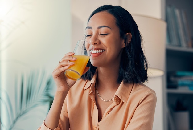 Bebida de suco de laranja e mulher negra feliz relaxam enquanto bebem líquido de saúde ou bebida de frutas orgânicas Sorriso de felicidade e nutricionista com sede com copo de suco para bem-estar e hidratação