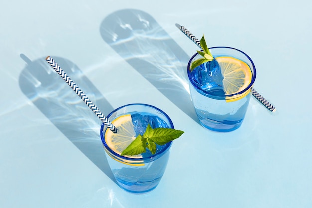 Bebida de verão. bebida refrescante fresca com hortelã e limão em copo. zero resíduos em casa. minimalismo. limonada fresca natural com sombras duras no fundo azul