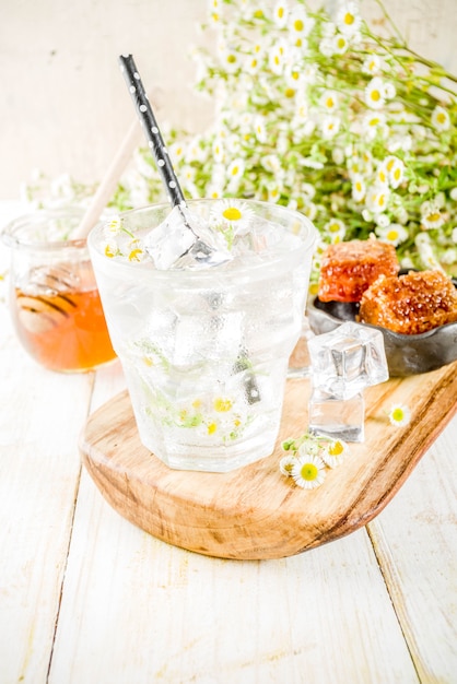 Bebida de verão dieta orgânica desintoxicação, infusão de água com camomila e mel, na mesa de madeira branca, com flores de camomila e mel em uma jarra. Copie o espaço