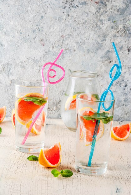 Bebida de desintoxicación refrescante de verano con toronja rosa y menta fresca, agua de frutas de spa, limonada o cóctel jin tonic, fondo de hormigón ligero