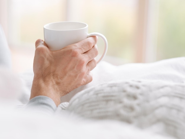 Bebida para despertarse Hombre sosteniendo una taza blanca de bebida caliente por la mañana