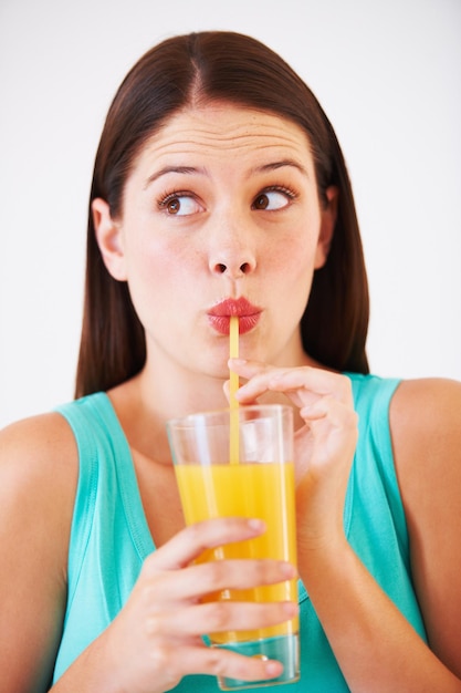 Foto bebida divertida y cara de mujer con jugo para nutrición bienestar e hidratación en el estudio bebida batido y persona sedienta con mezcla de frutas para vitaminas desintoxicación y dieta en fondo blanco