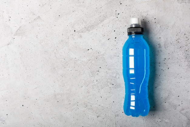 Bebida energética isotónica. Botellas con líquido transparente azul, bebida deportiva sobre un fondo de hormigón gris