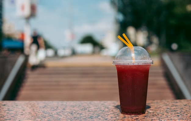 Bebida de frambuesa roja en un vaso de plástico con una pajita