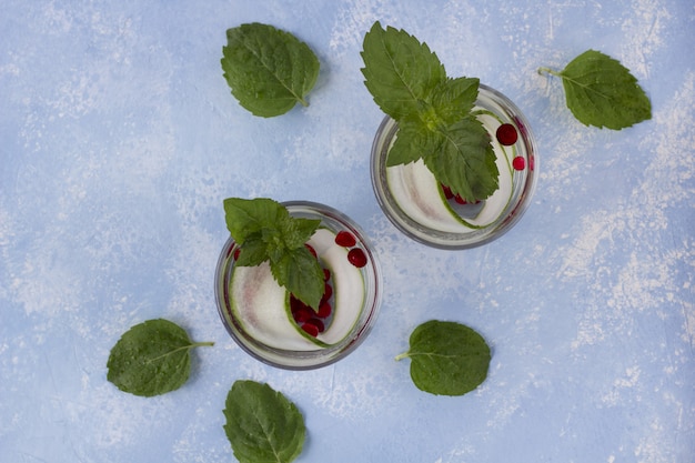 Bebida fresca de desintoxicación con pepino y bayas, limonada en un vaso con menta